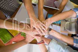 Students placing hands together over library table