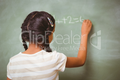 Rear view of little girl writing on blackboard
