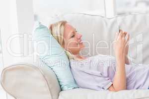 Woman listening music while lying on sofa