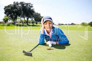 Female golfer looking at her ball on putting green