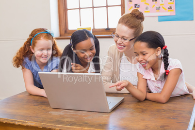 Teacher and pupils looking at laptop