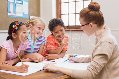 Teacher and pupils working at desk together