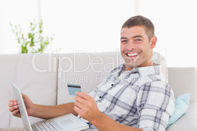 Happy man shopping online through laptop using credit card