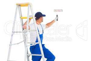 Handyman on ladder while using paint roller