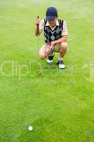 Crouching golfer looking at the ball