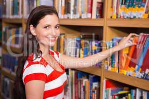 Student covering face with book in library