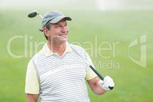 Golfer standing and swinging his club smiling at camera