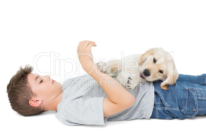 Puppy playing on boy lying over white background