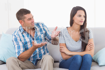 Man arguing with angry woman on sofa