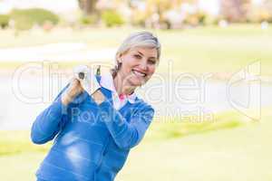 Female golfer standing holding her club smiling