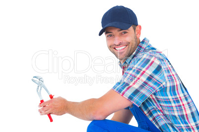 Happy handyman holding pliers on white background