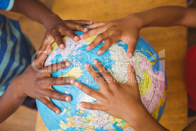 Hands on globe in classroom