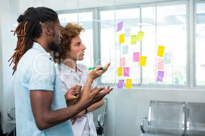 Creative team looking at adhesive notes in office