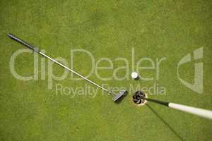 Golf club and golf ball on the putting green beside flag