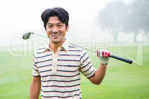 Golfer standing and holding his club smiling at camera