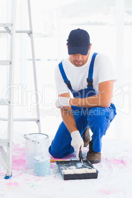 Handyman using paint roller in tray at home