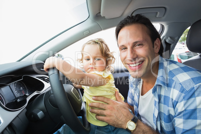 Father playing with baby in drivers seat