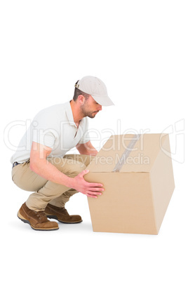 Delivery man crouching while picking cardboard box