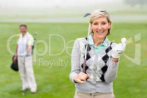 Lady golfer smiling at camera with partner behind