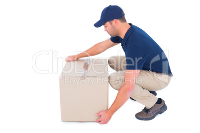 Delivery man crouching while picking cardboard box