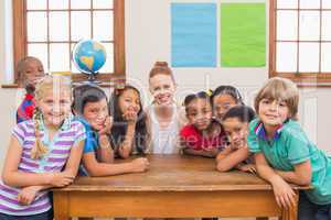 Cute pupils and teacher smiling at camera in classroom