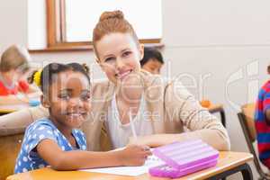 Pretty teacher helping pupil in classroom