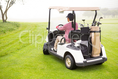 Golfer driving in his golf buggy