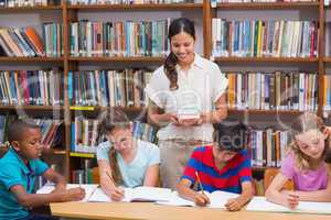 Pretty teacher helping pupils in library