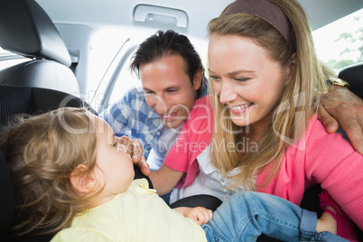 Parents securing baby in the car seat