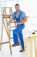 Carpenter with power drill climbing ladder at construction site
