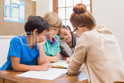 Teacher and pupils working at desk together