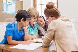 Teacher and pupils working at desk together