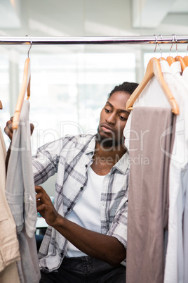 Male fashion designer looking at rack of clothes