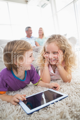 Brother and sister with digital tablet on rug