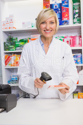 Smiling pharmacist scanning box of medicine