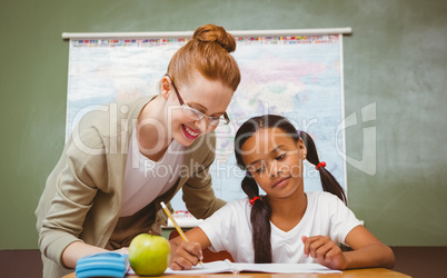 Teacher assisting little girl with homework in classroom