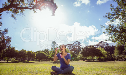 Pretty woman blowing bubbles in the park