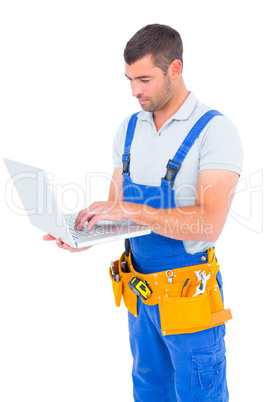 Carpenter in blue overalls using laptop
