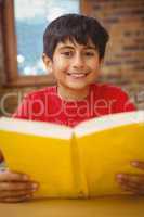 Portrait of boy reading book in library