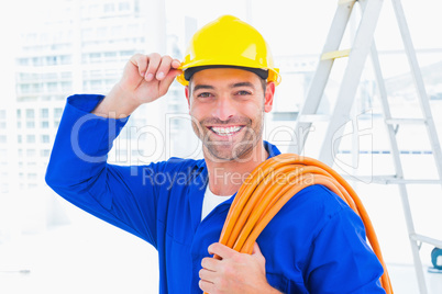 Confident repairman wearing hard hat while holding wire roll