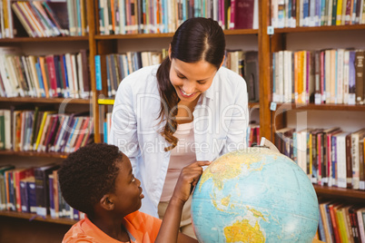 Teacher and boy looking at globe in library