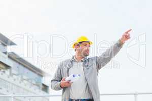Architect with blueprints pointing towards sky