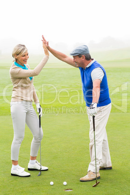 Golfing couple high fiving on the golf course