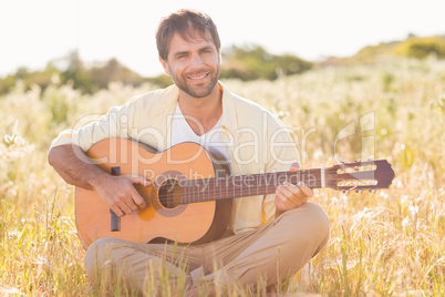 Happy man smiling and playing guitar