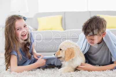 Siblings playing with puppy on rug