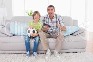 Happy boy watching soccer match with father on sofa