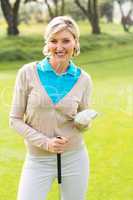 Cheerful golfer smiling at camera holding her club