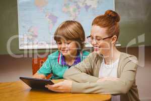 Teacher and boy using digital tablet in classroom