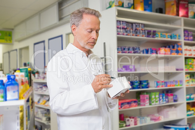 Focused pharmacist writing on box of medicine