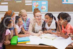 Teacher and pupils working at desk together